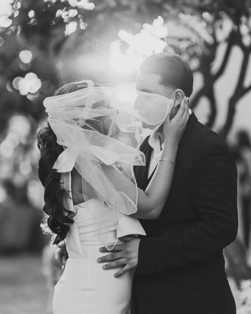 Recién casados besándose bajo el velo